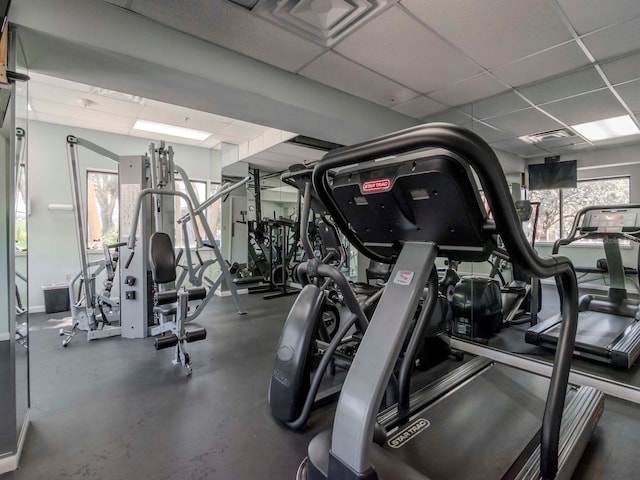 exercise room with visible vents, a paneled ceiling, and baseboards