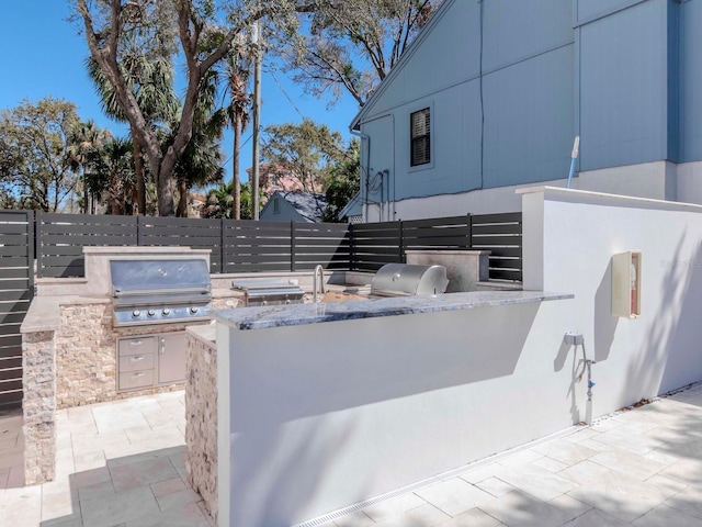 view of patio with a grill, exterior kitchen, and fence