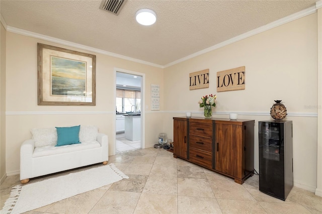 living area with visible vents, a textured ceiling, beverage cooler, and crown molding