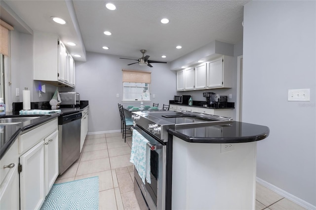 kitchen with light tile patterned floors, stainless steel appliances, white cabinetry, dark countertops, and a center island