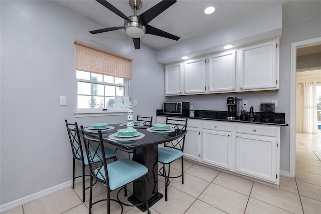 kitchen featuring stainless steel microwave, dark countertops, white cabinets, and a ceiling fan