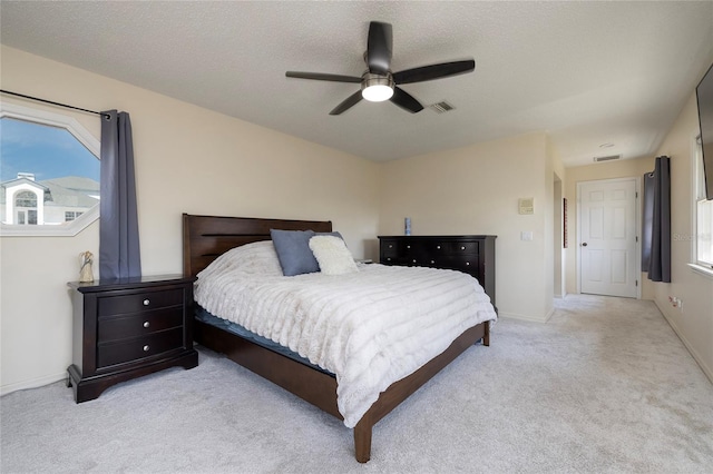 bedroom with visible vents, light carpet, a textured ceiling, and ceiling fan