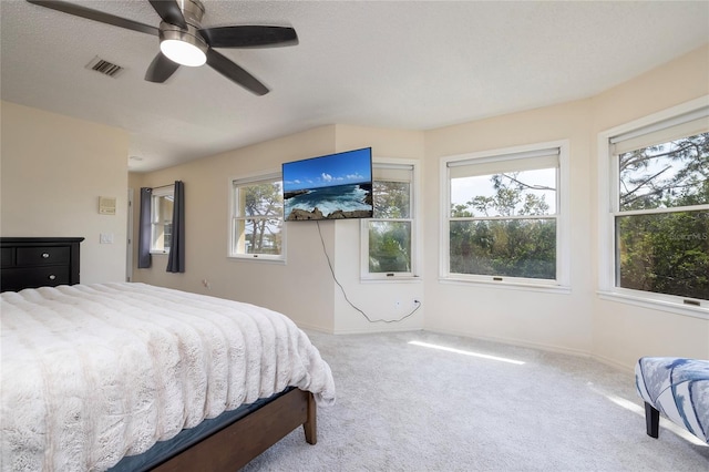 carpeted bedroom featuring multiple windows, baseboards, visible vents, and ceiling fan