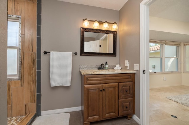 full bath featuring vanity, a shower, and baseboards