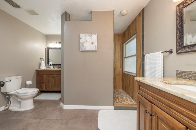 bathroom featuring two vanities, toilet, baseboards, and visible vents