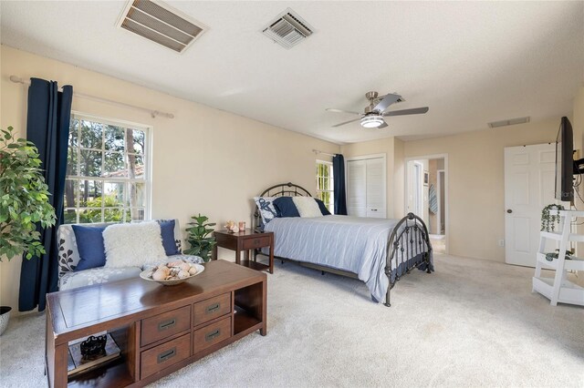 bedroom with light carpet, visible vents, and ensuite bath