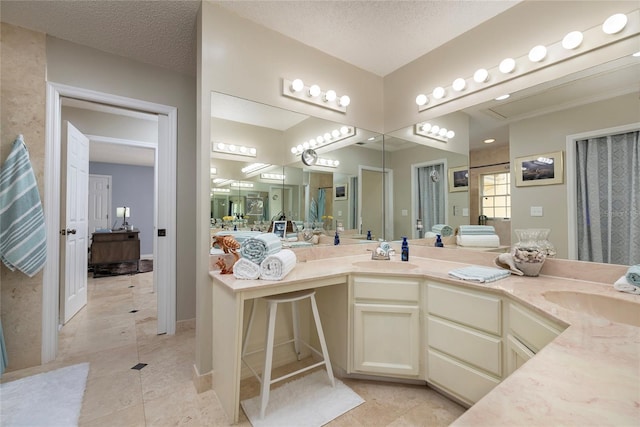 ensuite bathroom featuring a textured ceiling, double vanity, and a sink