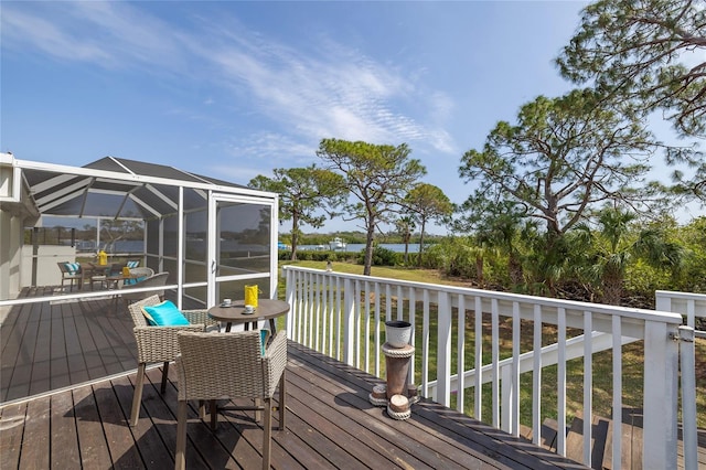 deck with glass enclosure, outdoor dining area, and a water view