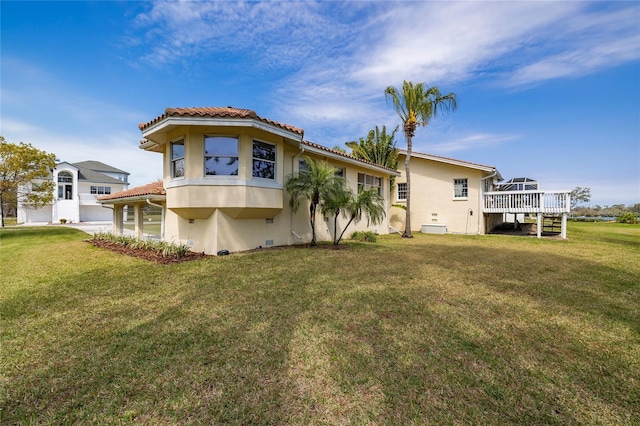 back of property featuring a tiled roof, a yard, and stucco siding