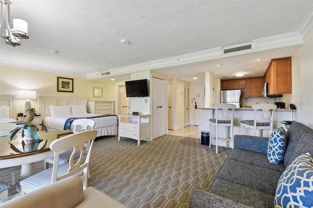 bedroom featuring freestanding refrigerator, visible vents, crown molding, and a textured ceiling