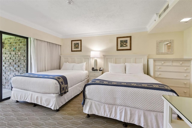 bedroom with a textured ceiling, wainscoting, visible vents, and crown molding