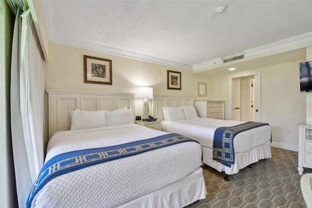 bedroom with visible vents, dark colored carpet, a textured ceiling, crown molding, and a decorative wall