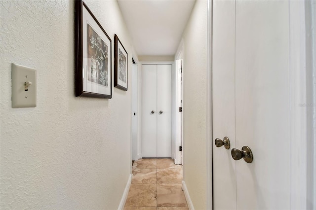 hallway with a textured wall and baseboards