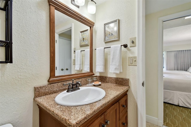 ensuite bathroom featuring vanity, connected bathroom, and a textured wall