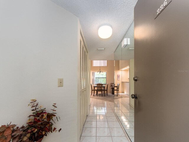 hallway featuring light tile patterned floors and a textured ceiling