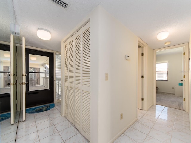 corridor featuring baseboards, visible vents, marble finish floor, and a textured ceiling