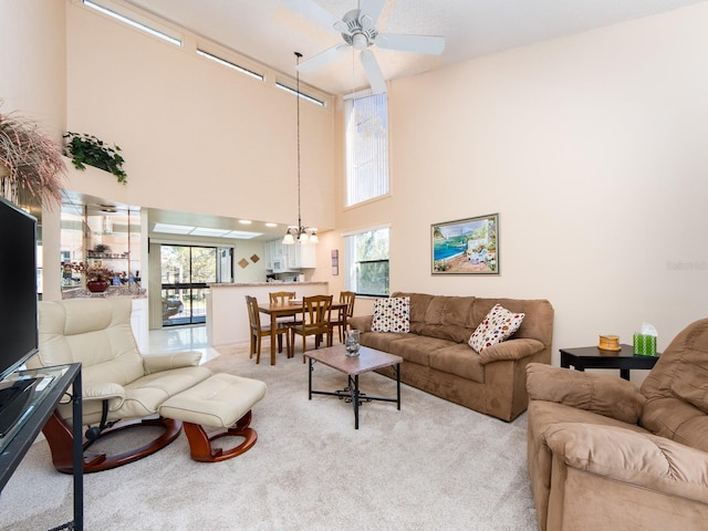 living area featuring light colored carpet and ceiling fan with notable chandelier