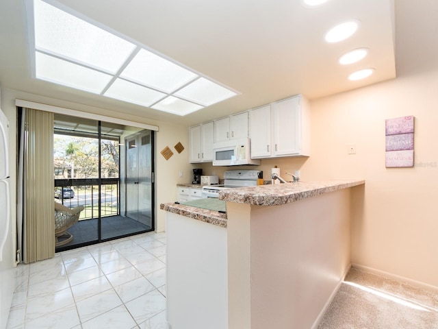 kitchen with baseboards, light countertops, a peninsula, white cabinets, and white appliances