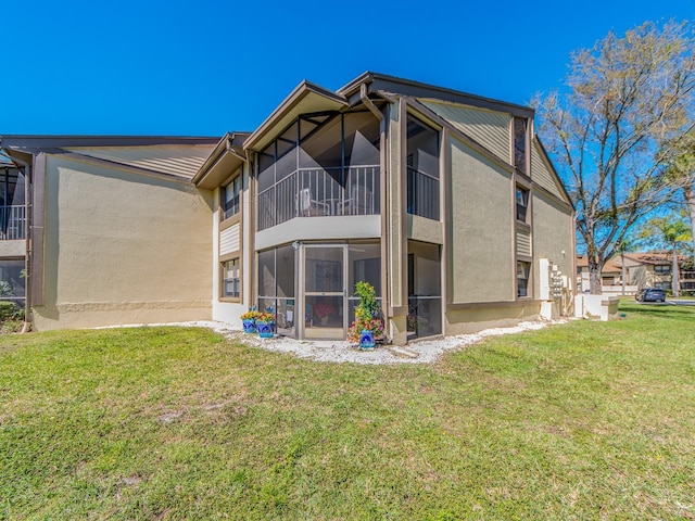 back of house with a yard, stucco siding, and a sunroom