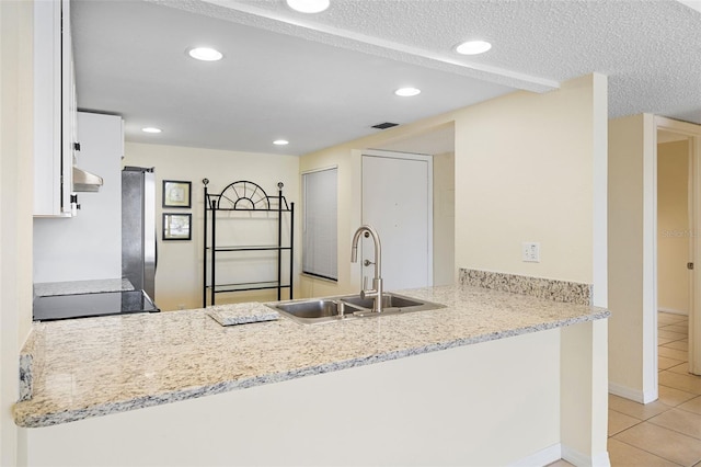 kitchen with white cabinets, a peninsula, a sink, and light tile patterned floors