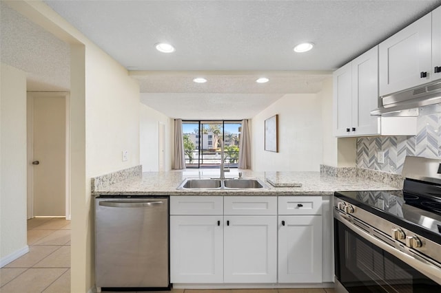 kitchen featuring light stone countertops, under cabinet range hood, white cabinetry, and appliances with stainless steel finishes