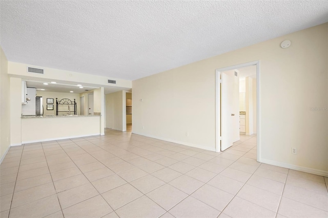 unfurnished living room with a textured ceiling, visible vents, baseboards, and light tile patterned floors