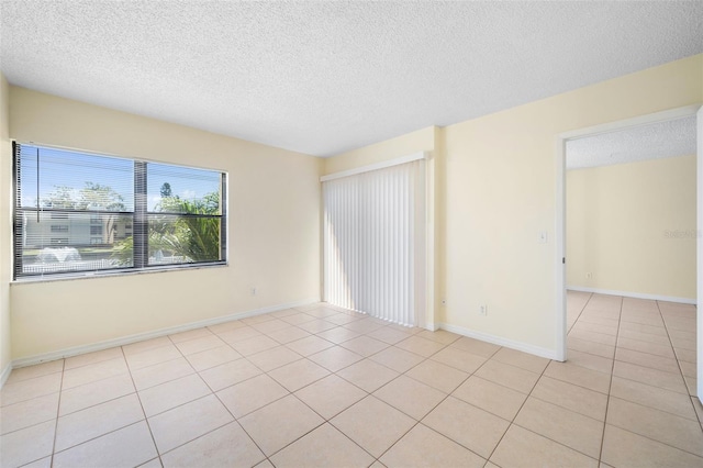 empty room featuring baseboards, light tile patterned flooring, and a textured ceiling
