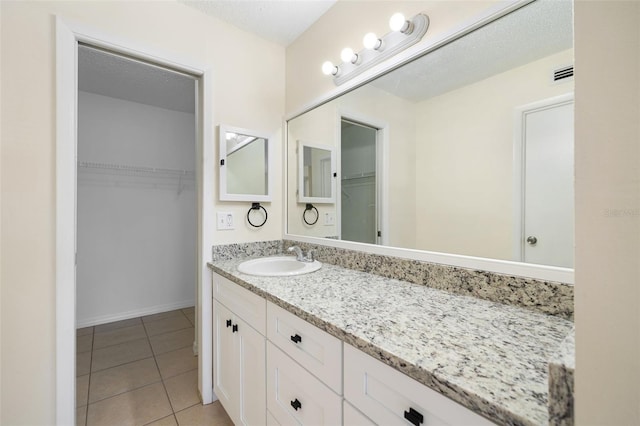 bathroom featuring a spacious closet, visible vents, tile patterned floors, and vanity