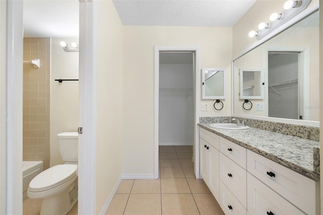 full bath with a spacious closet, toilet, vanity, and tile patterned floors