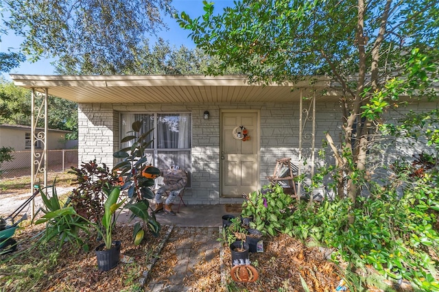 entrance to property with brick siding and fence