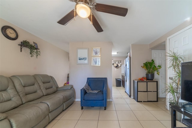 living area featuring light tile patterned floors, ceiling fan, and baseboards