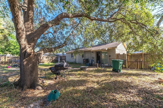 rear view of property featuring fence and central AC