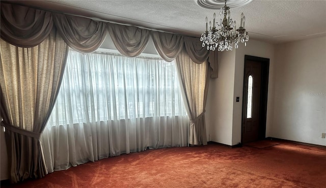 carpeted spare room with a notable chandelier and a textured ceiling