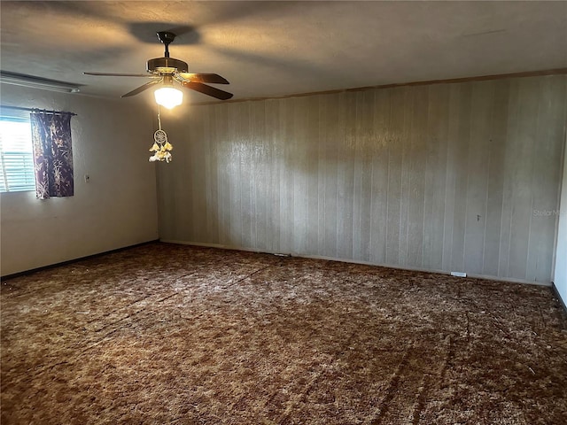 carpeted spare room with ceiling fan and wooden walls