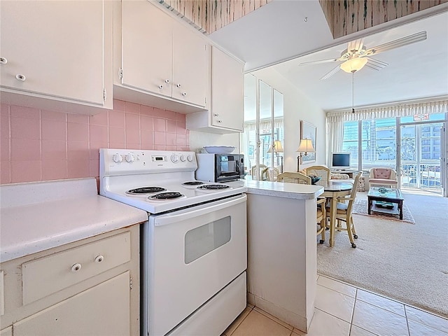 kitchen featuring tasteful backsplash, light countertops, light carpet, white cabinets, and white electric stove