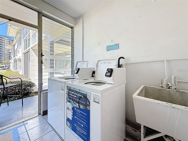 community laundry room featuring a sink, light tile patterned flooring, and washer and dryer