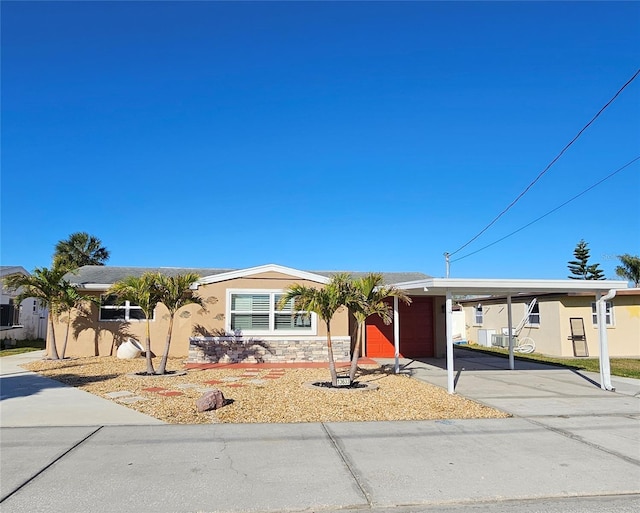 view of front of property with a carport, an attached garage, driveway, and stucco siding