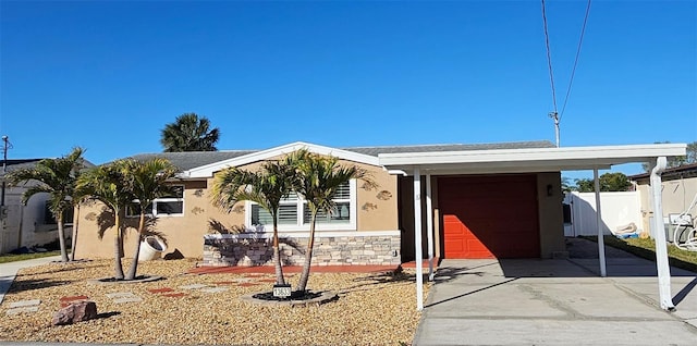 view of front of house with fence, concrete driveway, stucco siding, stone siding, and an attached garage