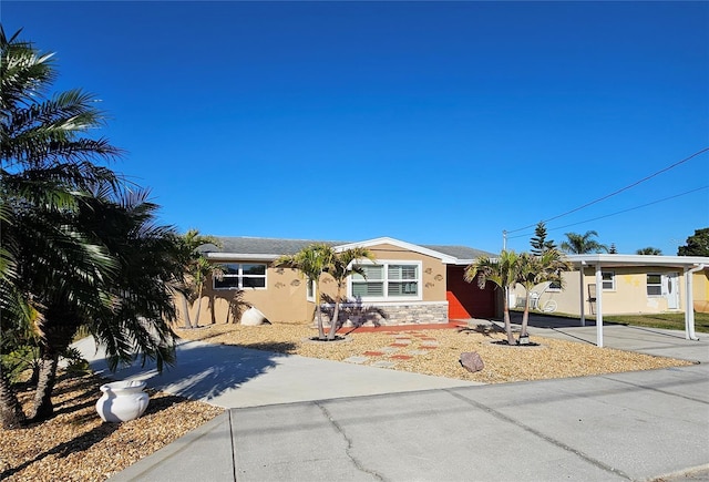 ranch-style home with stucco siding, stone siding, and driveway