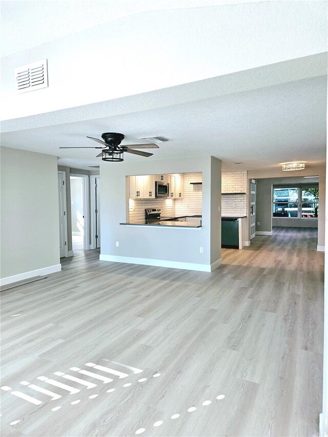 13633 Britton Dr, Hudson, FL 34667 - unfurnished living room with visible vents, baseboards, light wood-style floors, and a textured ceiling