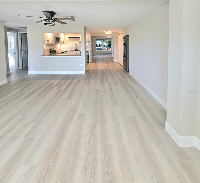 13633 Britton Dr, Hudson, FL 34667 - unfurnished living room featuring baseboards, light wood-type flooring, and a ceiling fan