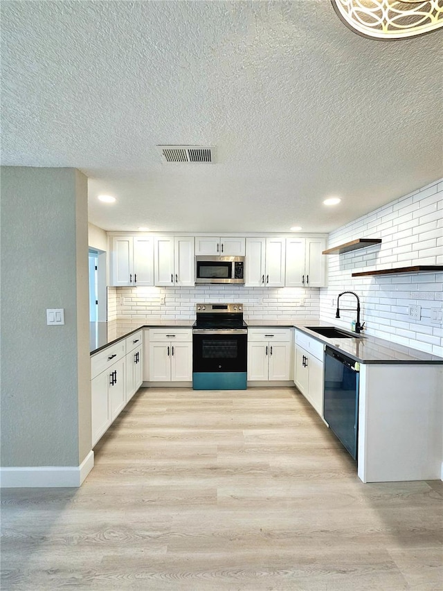 13633 Britton Dr, Hudson, FL 34667 - kitchen with tasteful backsplash, light wood-type flooring, white cabinetry, a sink, and stainless steel appliances