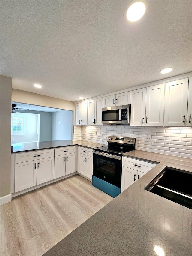 13633 Britton Dr, Hudson, FL 34667 - kitchen with a sink, white cabinetry, light wood finished floors, stainless steel appliances, and backsplash