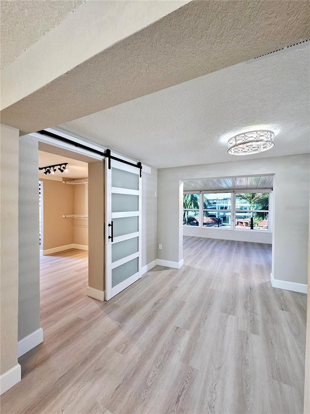 13633 Britton Dr, Hudson, FL 34667 - interior space featuring a barn door, baseboards, a textured ceiling, and wood finished floors