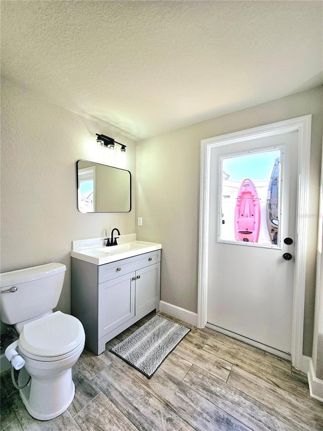 13633 Britton Dr, Hudson, FL 34667 - bathroom featuring baseboards, toilet, a textured ceiling, vanity, and wood finished floors