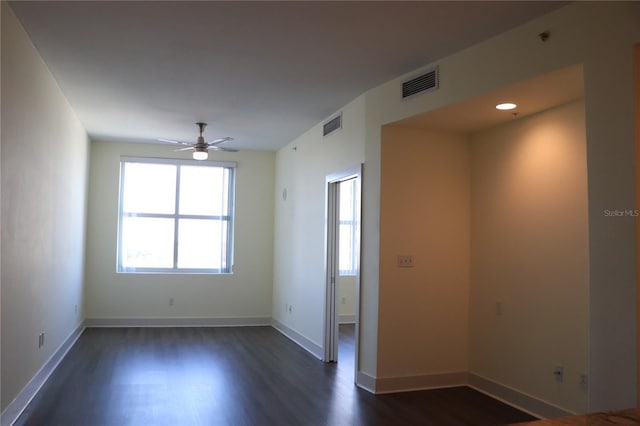 spare room featuring dark wood finished floors, visible vents, and baseboards