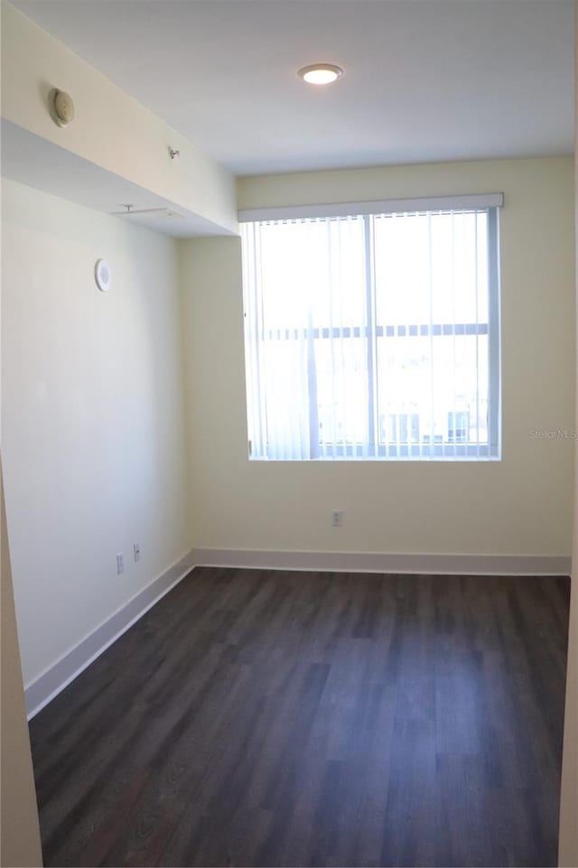 empty room with baseboards and dark wood-type flooring