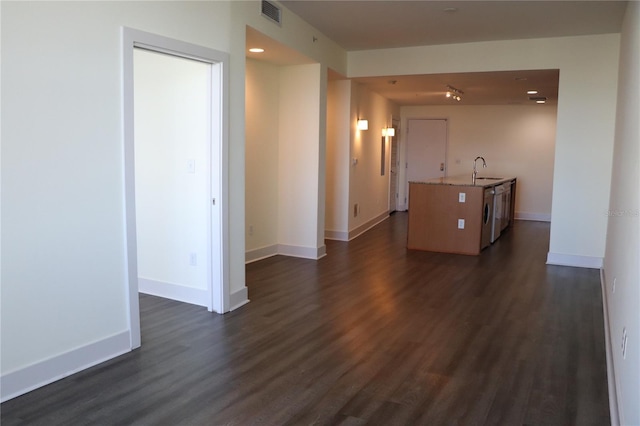 hallway with dark wood-type flooring, visible vents, a sink, and baseboards