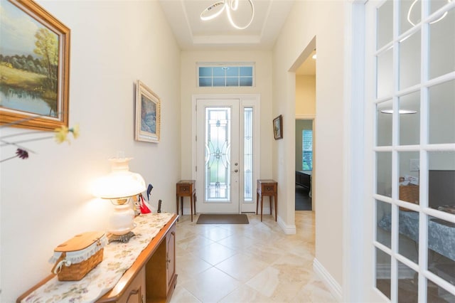 entrance foyer featuring light tile patterned floors, baseboards, and an inviting chandelier