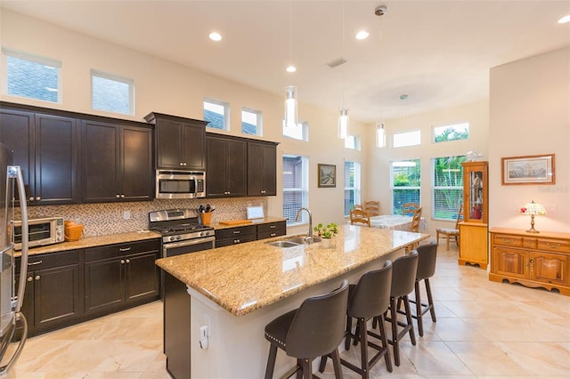 kitchen with light stone countertops, visible vents, a sink, stainless steel appliances, and tasteful backsplash